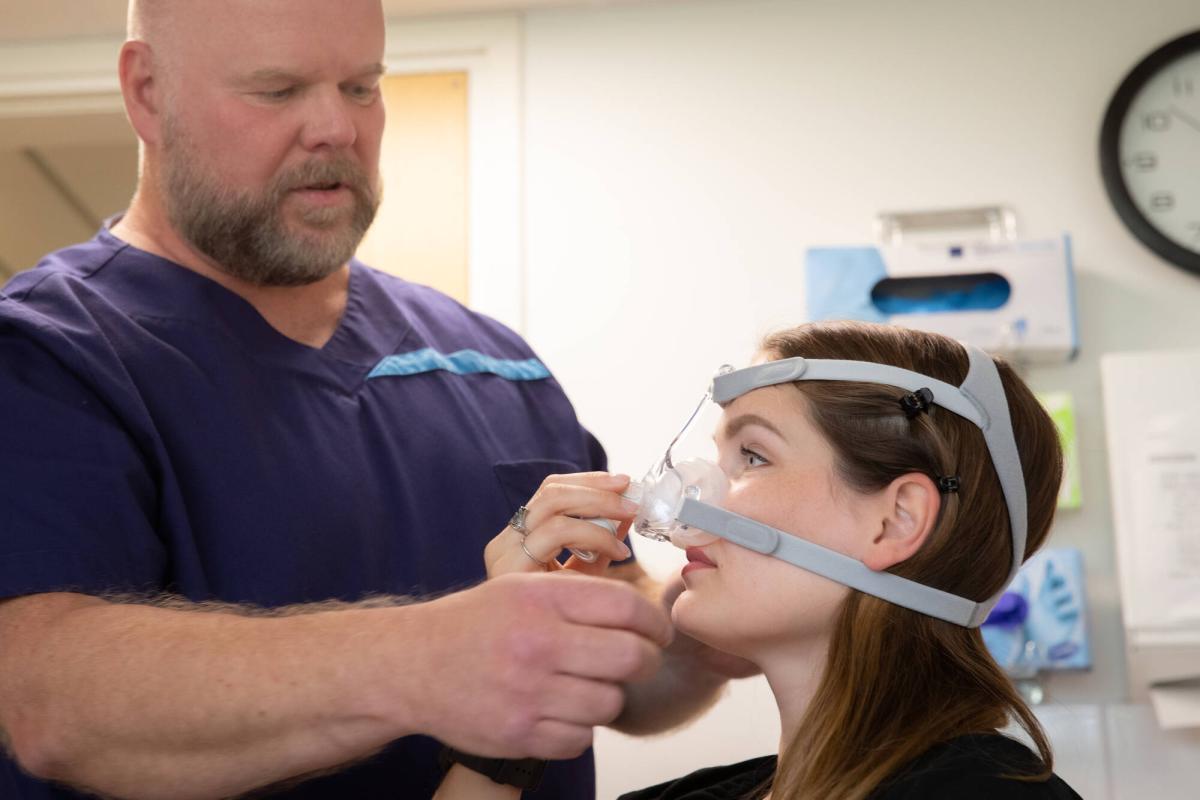 Hoitaja sovittaa potilaalle CPAP-laitetta