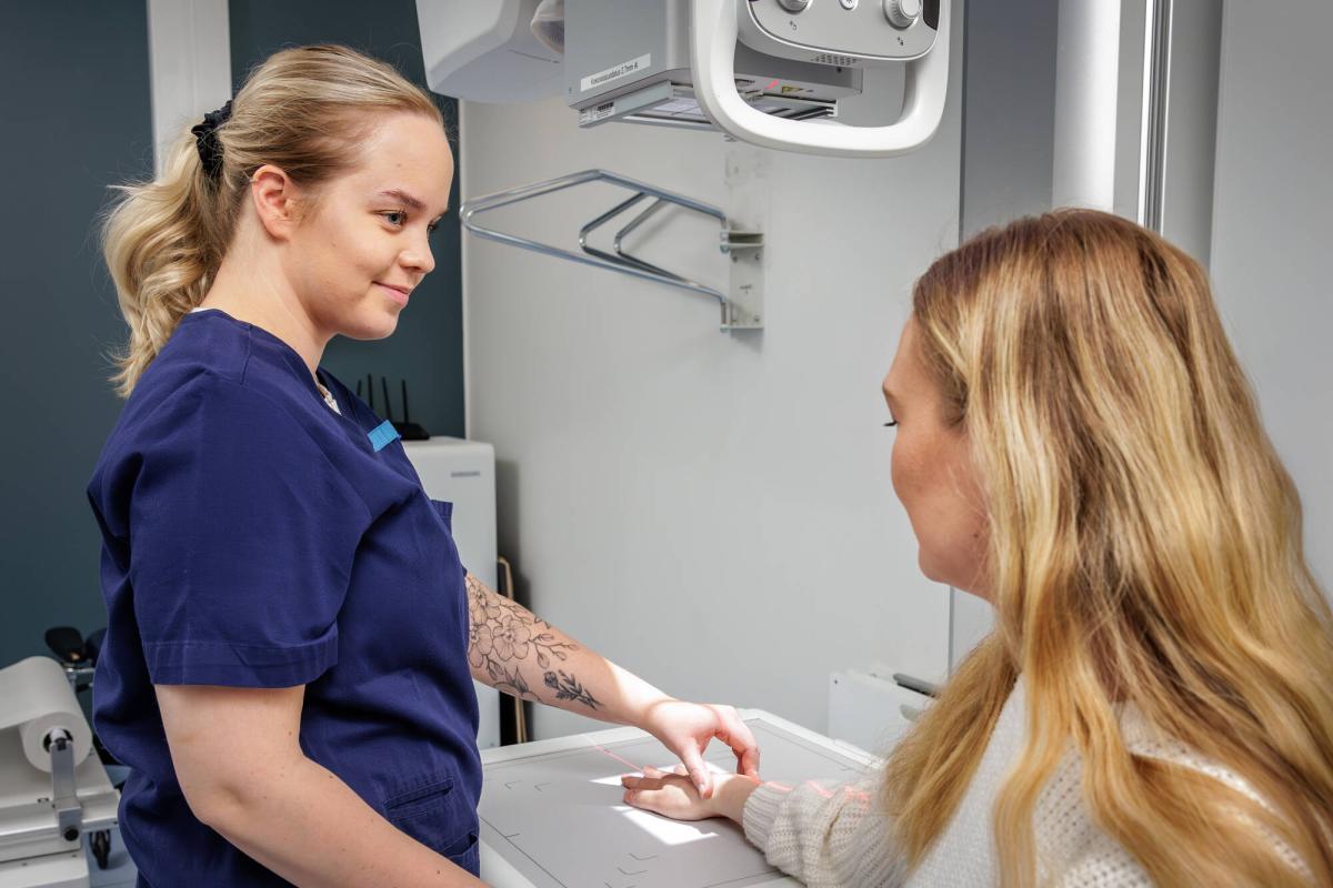 A radiographer preparing a patient for a hand X-ray.