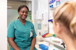 A laboratory nurse discussing with a patient. The patient is partly visible from behind.
