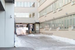 White building walls on both sides. In the back a tunnel and beside it an entrance. 